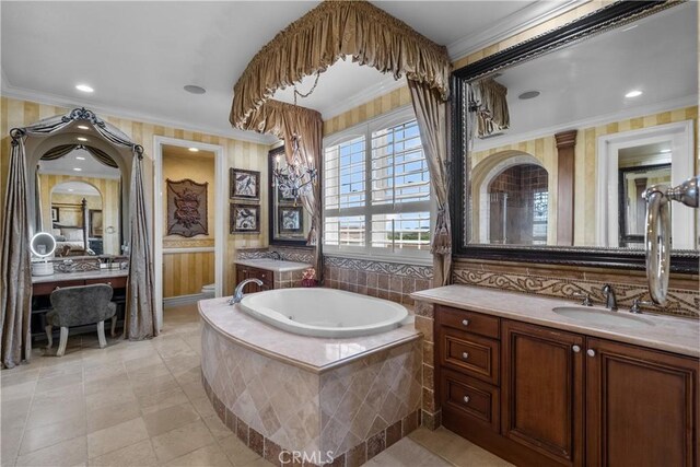 bathroom featuring vanity, ornamental molding, and tiled tub