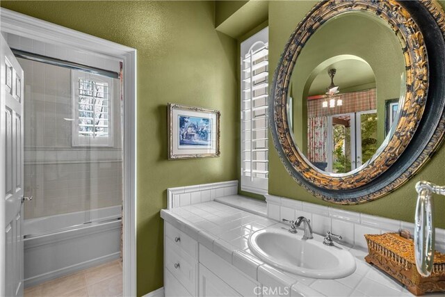 bathroom with ceiling fan, enclosed tub / shower combo, vanity, and tile patterned flooring