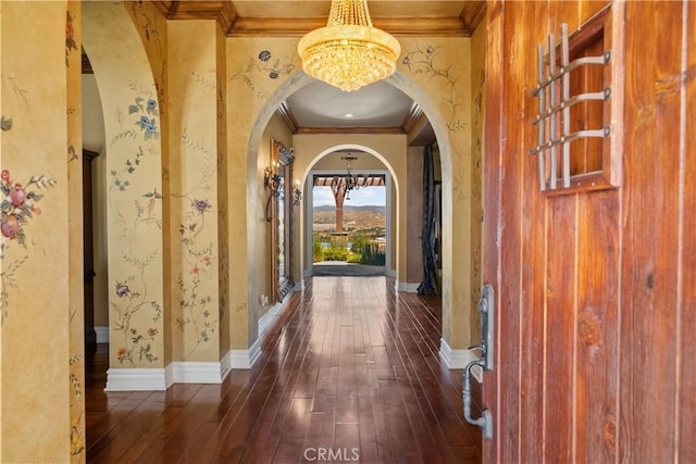 hallway featuring dark wood-type flooring, crown molding, and an inviting chandelier