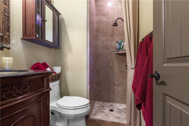 bathroom featuring a tile shower, vanity, and toilet