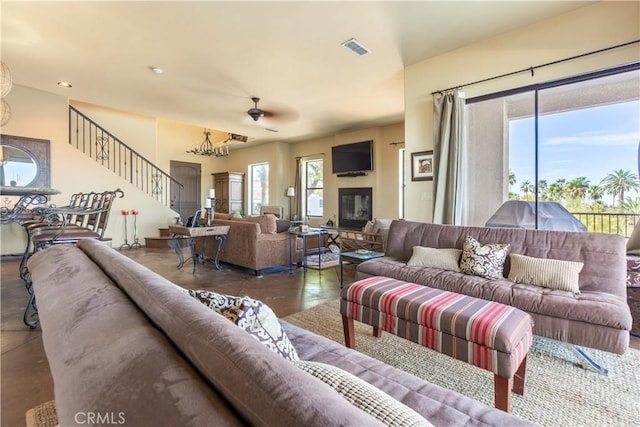 living room with ceiling fan with notable chandelier and dark hardwood / wood-style floors