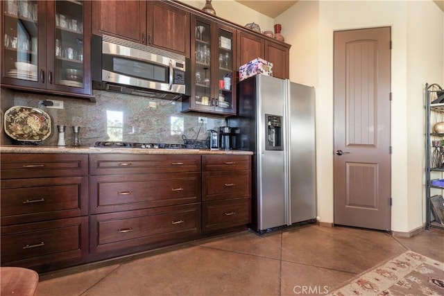 kitchen with light tile patterned floors, backsplash, stainless steel appliances, and dark brown cabinetry