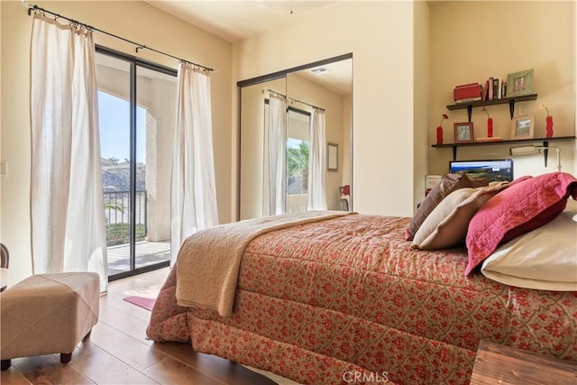 bedroom featuring access to outside, multiple windows, and hardwood / wood-style floors