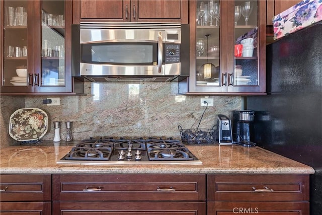 kitchen with decorative backsplash, appliances with stainless steel finishes, and light stone countertops