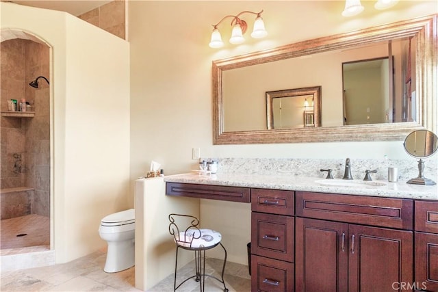 bathroom featuring tiled shower, vanity, and toilet