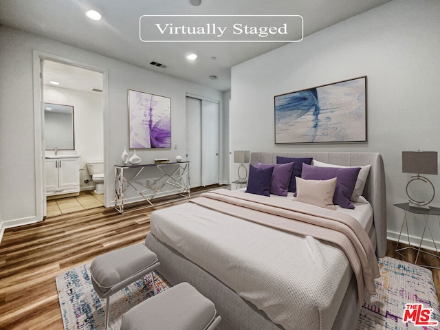 bedroom featuring sink, hardwood / wood-style flooring, and ensuite bathroom