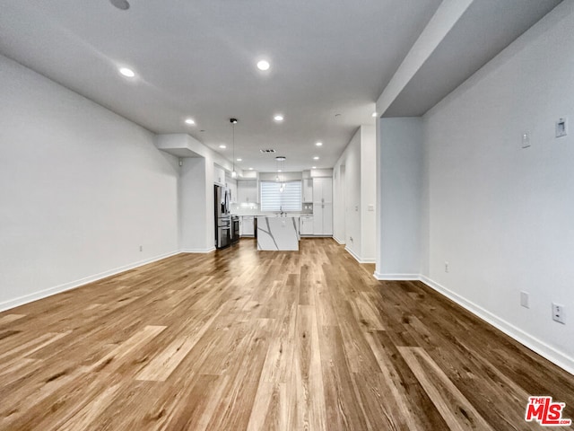 unfurnished living room featuring light wood-type flooring and sink