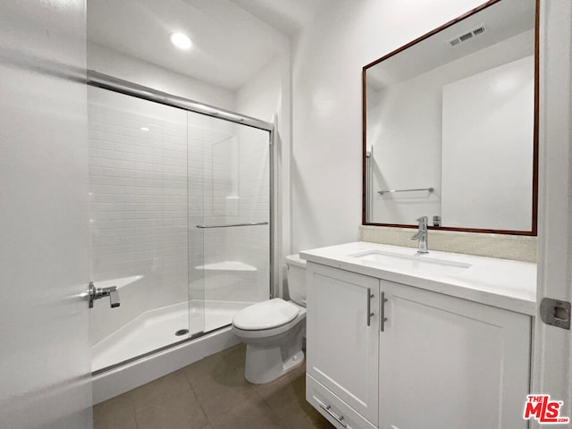 bathroom featuring tile patterned flooring, toilet, an enclosed shower, and vanity