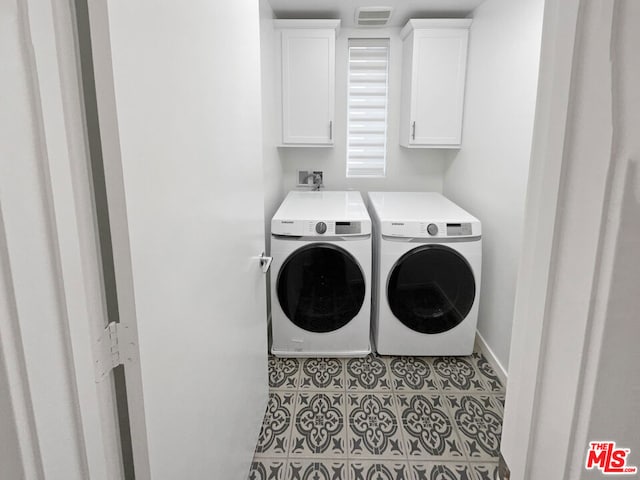 laundry area with washer and clothes dryer, light tile patterned floors, and cabinets