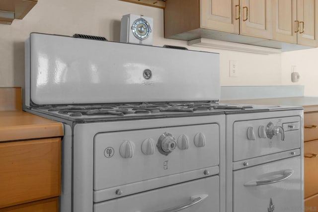 room details featuring light brown cabinetry and white range with gas cooktop