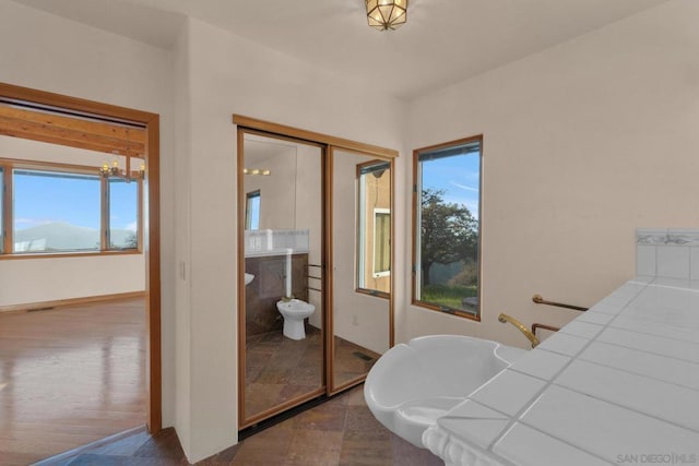 bedroom with multiple windows, wood-type flooring, a closet, and a notable chandelier