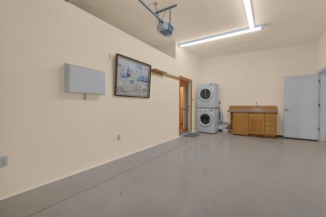 garage featuring a garage door opener, stacked washer and clothes dryer, and sink