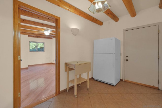 interior space with white fridge, light tile patterned floors, and beamed ceiling