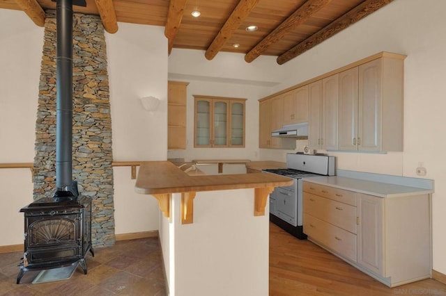 kitchen with range with gas stovetop, light brown cabinetry, a wood stove, and a breakfast bar