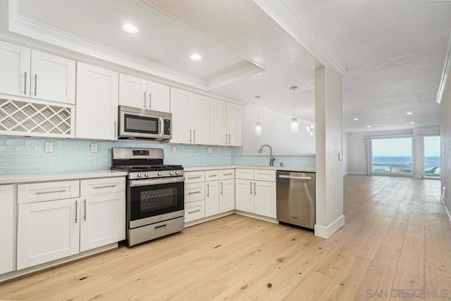 kitchen with white cabinetry, hanging light fixtures, stainless steel appliances, and light hardwood / wood-style floors