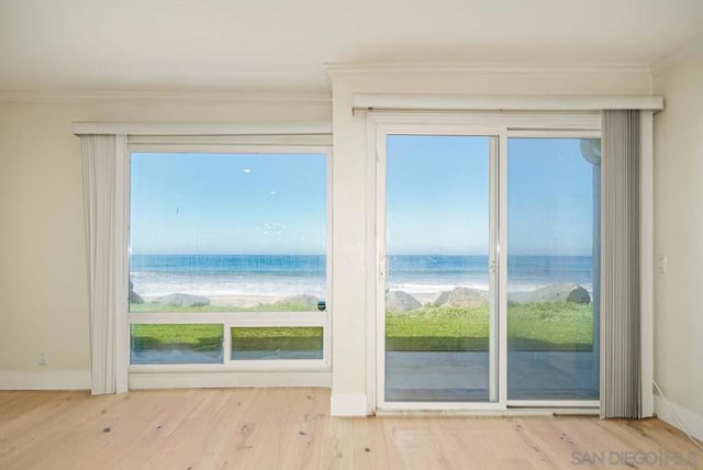 doorway with a water view, light hardwood / wood-style floors, and ornamental molding