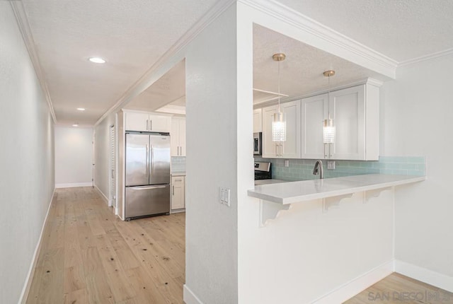 kitchen featuring pendant lighting, a kitchen breakfast bar, light hardwood / wood-style floors, white cabinetry, and stainless steel appliances