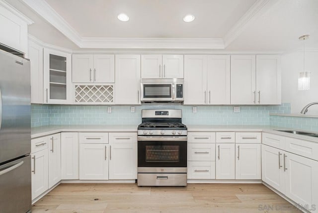 kitchen with pendant lighting, white cabinets, sink, light hardwood / wood-style flooring, and appliances with stainless steel finishes