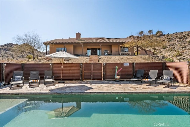 rear view of property featuring a patio area and a fenced in pool