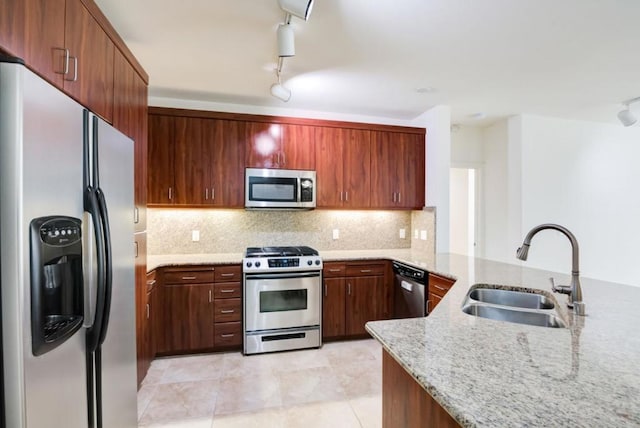 kitchen featuring tasteful backsplash, kitchen peninsula, sink, stainless steel appliances, and light stone counters