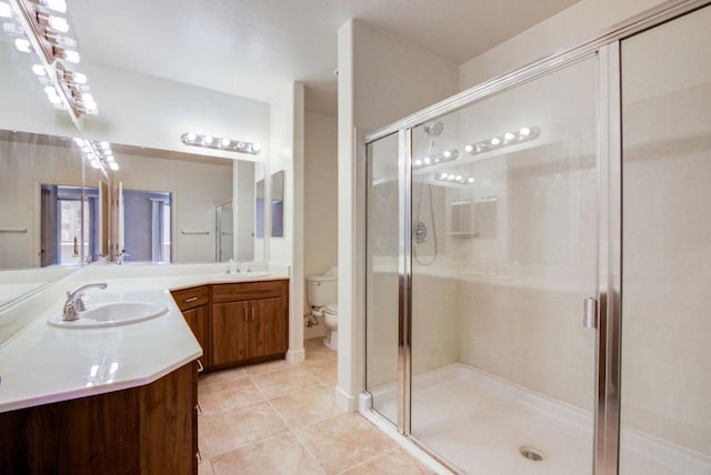 bathroom featuring toilet, tile patterned flooring, a shower with shower door, and vanity