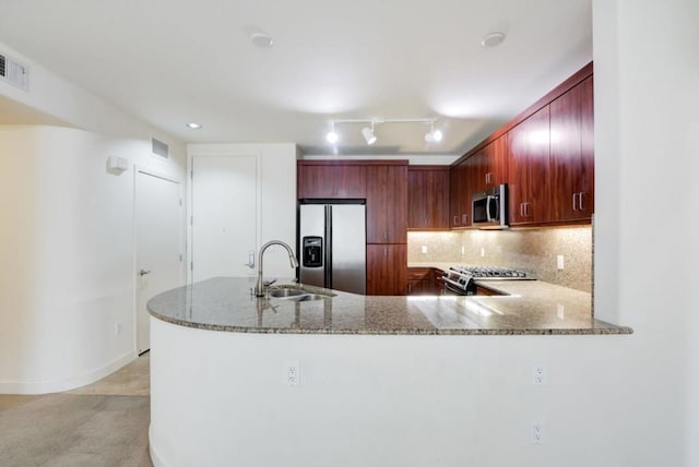 kitchen featuring light stone countertops, stainless steel appliances, tasteful backsplash, sink, and kitchen peninsula