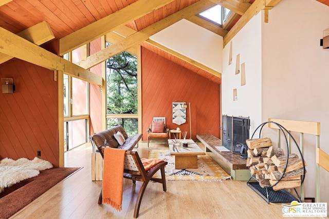 sitting room with a skylight, high vaulted ceiling, beam ceiling, wooden walls, and hardwood / wood-style flooring