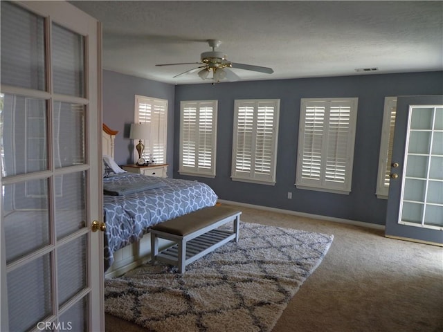 carpeted bedroom featuring ceiling fan and a textured ceiling