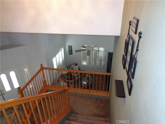 stairway featuring ceiling fan