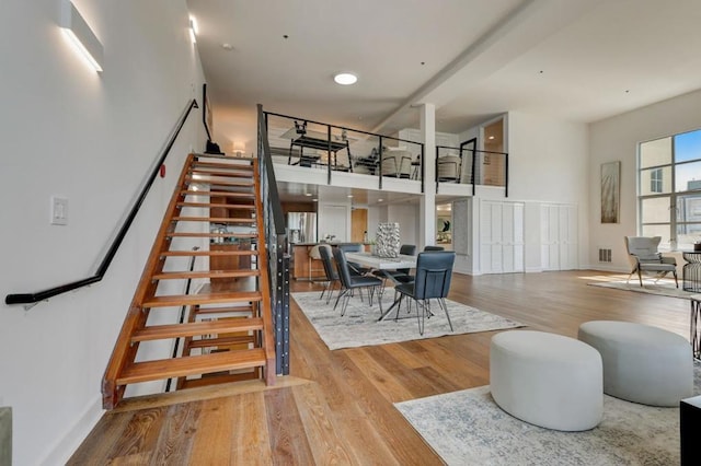 staircase with wood-type flooring and a towering ceiling