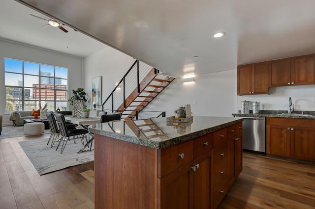 kitchen with a kitchen island, dark stone countertops, sink, dark hardwood / wood-style floors, and stainless steel dishwasher