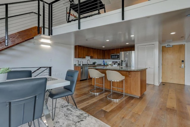 kitchen with appliances with stainless steel finishes, a kitchen island, light hardwood / wood-style floors, sink, and a breakfast bar