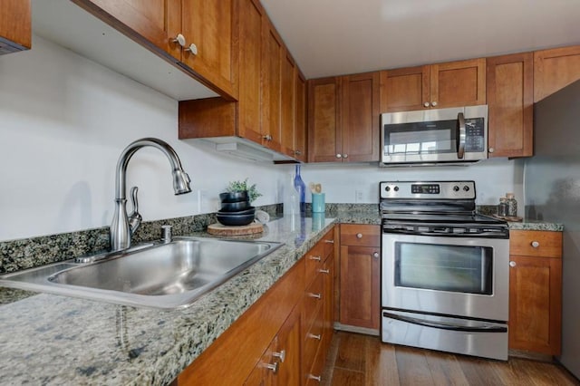 kitchen with stainless steel appliances, dark hardwood / wood-style floors, light stone counters, and sink