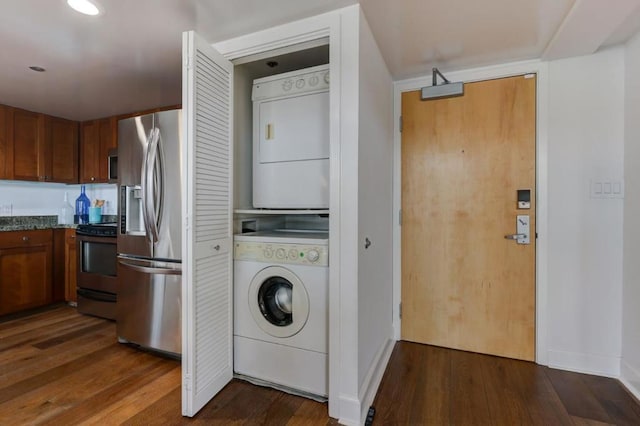 washroom with stacked washer and dryer and dark hardwood / wood-style flooring