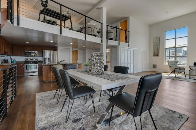 dining area with dark wood-type flooring, a high ceiling, and sink