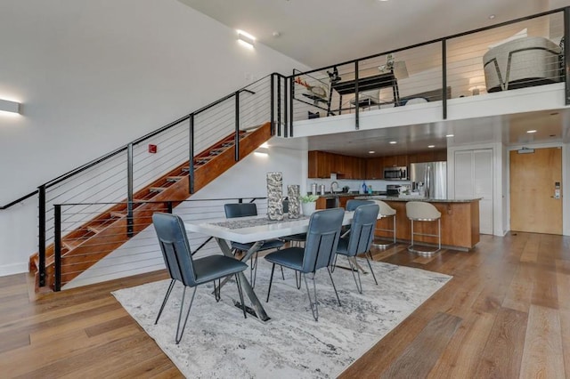 dining area with light wood-type flooring and a high ceiling