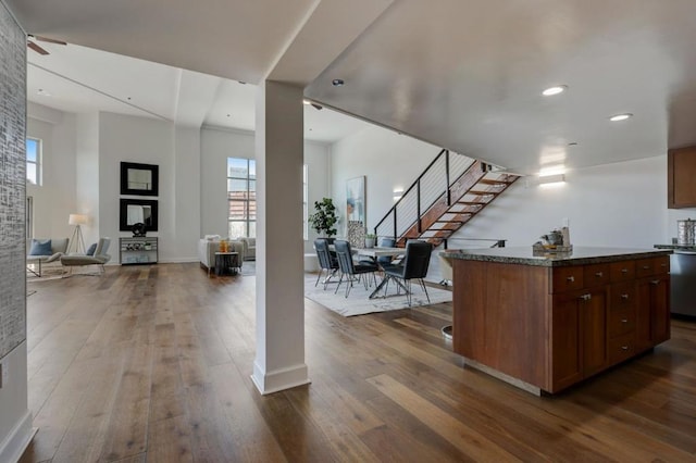 kitchen with a kitchen island, dark hardwood / wood-style floors, and dark stone counters