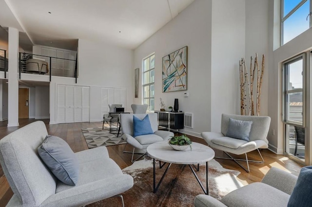 living room featuring a high ceiling, a wealth of natural light, and wood-type flooring