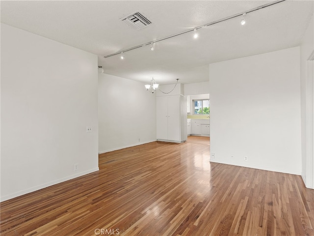 1901 Peyton Ave Unit T, Burbank, CA 91504 - unfurnished room featuring track lighting, a textured ceiling, a notable chandelier, and hardwood / wood-style floors