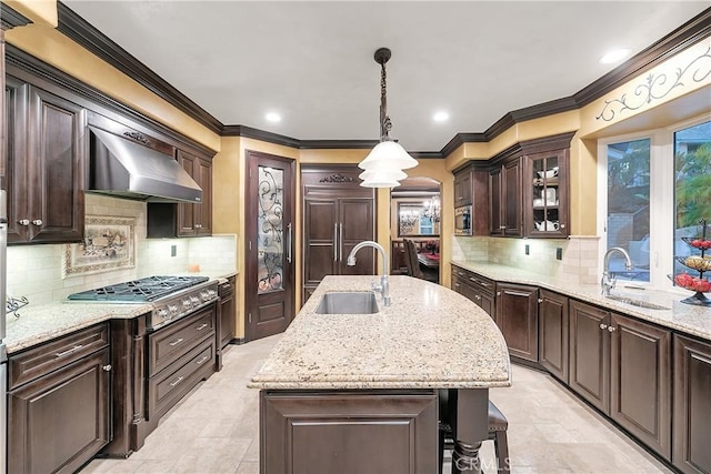 kitchen with decorative backsplash, sink, a center island with sink, and wall chimney exhaust hood