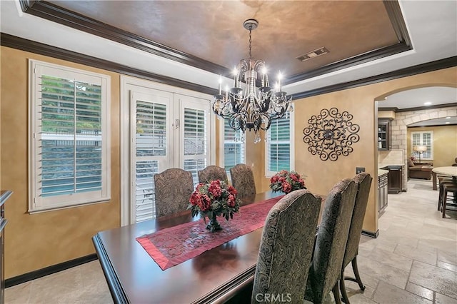 dining area with ornamental molding, a raised ceiling, and a notable chandelier