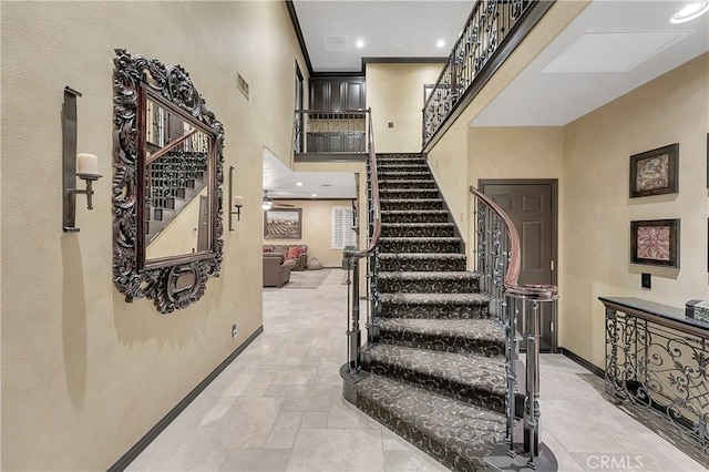 stairway featuring ceiling fan and a high ceiling