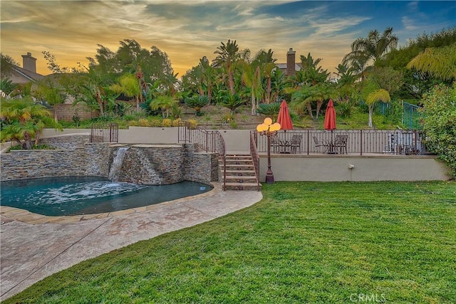 yard at dusk featuring pool water feature