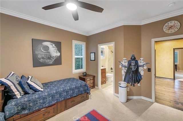 carpeted bedroom featuring ceiling fan, ensuite bathroom, and crown molding