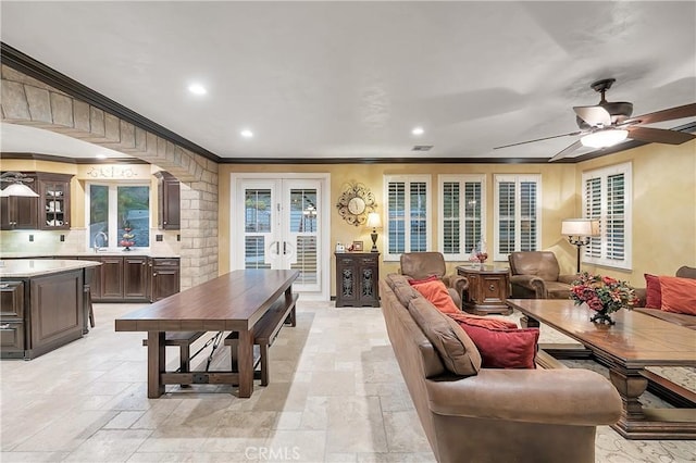 living room with ceiling fan, sink, and ornamental molding