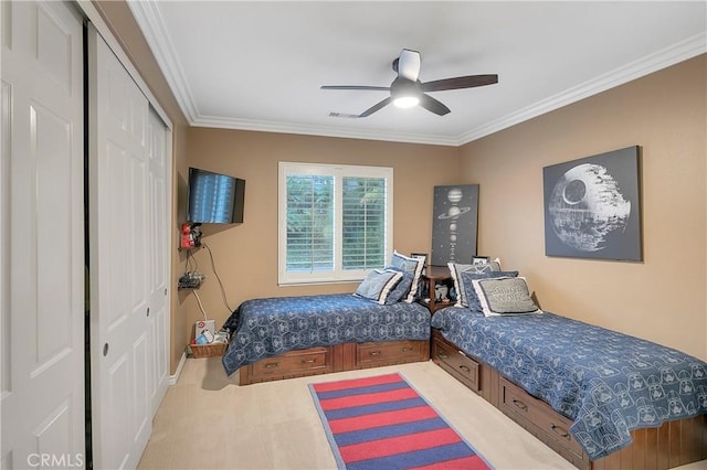 bedroom featuring ceiling fan, carpet, crown molding, and a closet