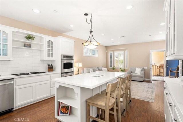 kitchen with decorative light fixtures, a kitchen island, white cabinetry, and stainless steel appliances