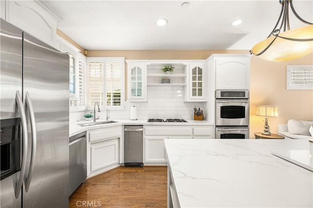 kitchen with sink, tasteful backsplash, pendant lighting, stainless steel appliances, and white cabinets