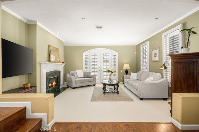 living room featuring crown molding, a fireplace, and light wood-type flooring