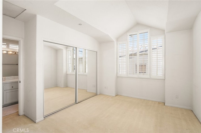 unfurnished bedroom featuring lofted ceiling, light carpet, and a closet